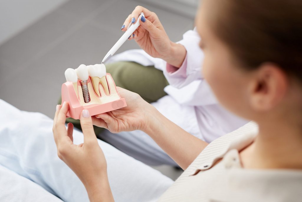 Dentist explaining dental implants procedure to female patient