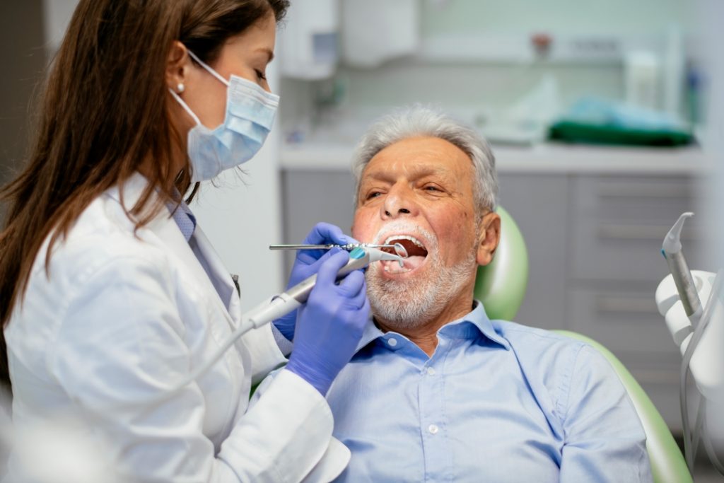 Periodontist checking a man's loose tooth