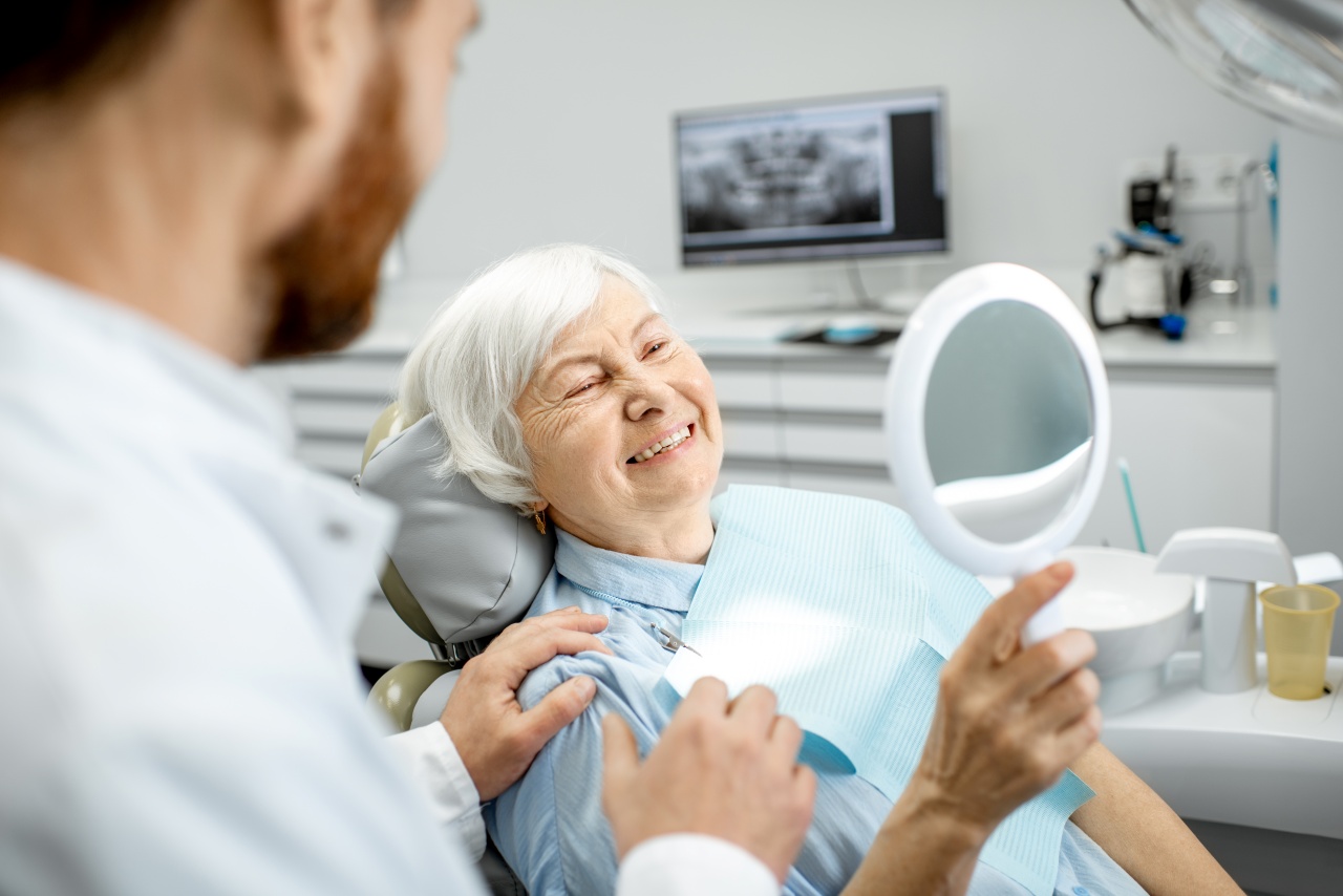 Senior women smiling with dental implants in dental chair