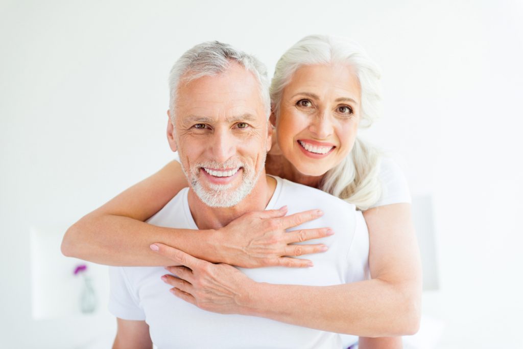 Senior dental restoration couple hugging and smiling