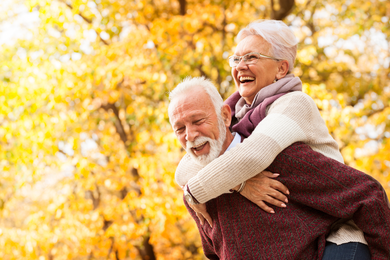 Senior man giving wife a piggy back ride