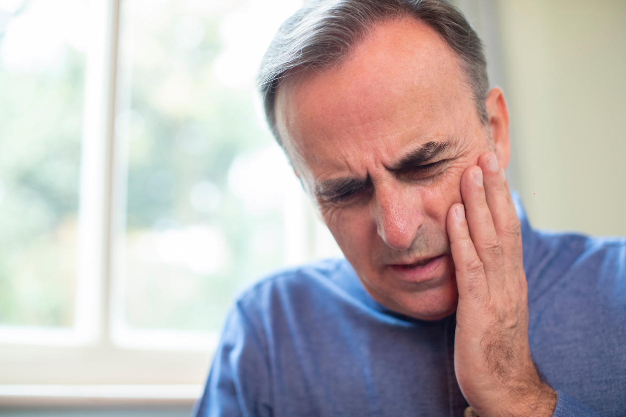 man holding cheek in pain from periodontal disease