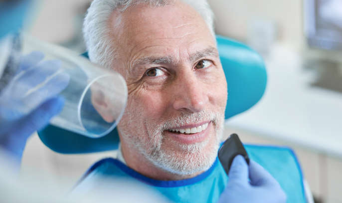 Senior man sitting in dental chair smiling