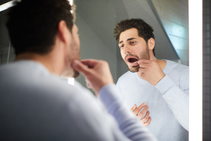 Man checking his teeth in the bathroom mirror