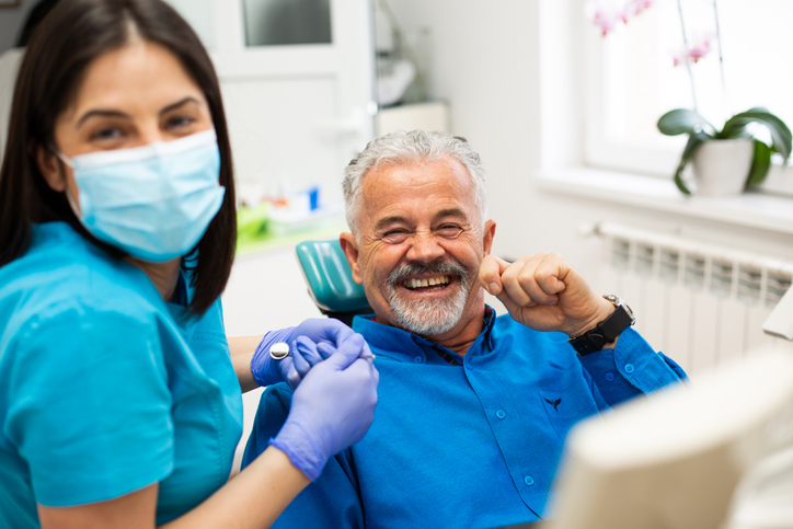 Man in dental chair smiling with hygienist