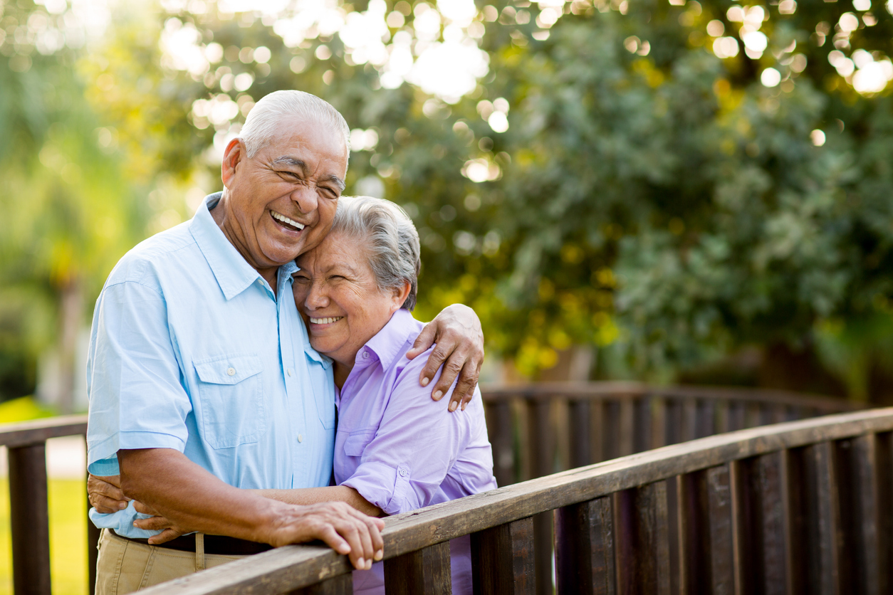 Elderly couple hugging and smiling on a bridge