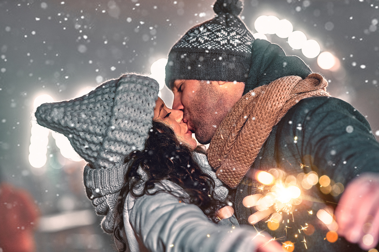 A couple kissing outside in snow for New Years