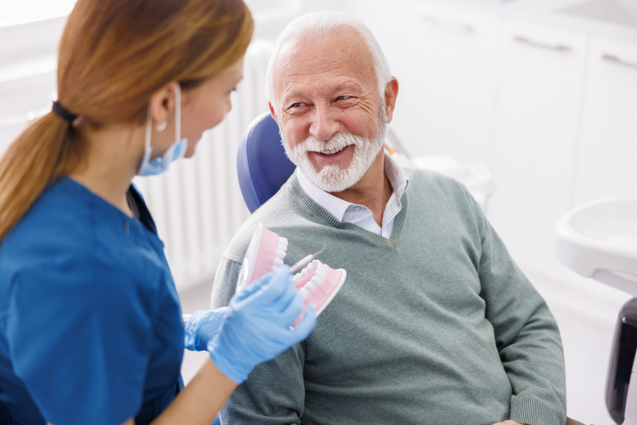 Male periodontal patient in dental chair smiling with dental hygienist