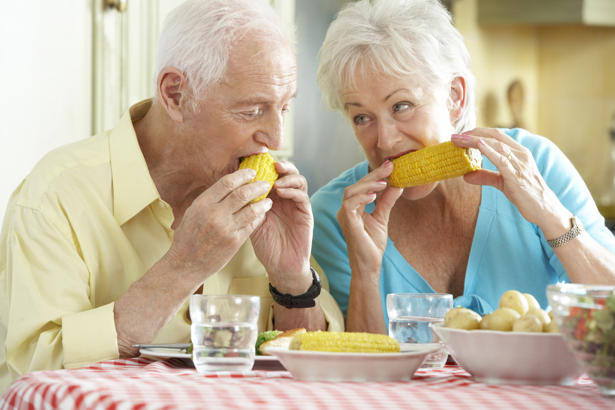 Senior couple eating corn on the cob.